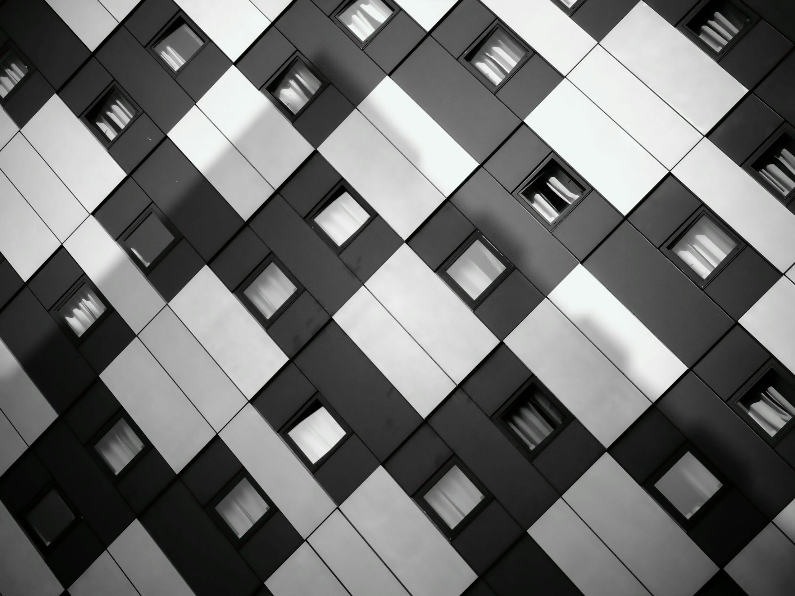 A striking monochrome image of a modern building's geometric facade with windows.